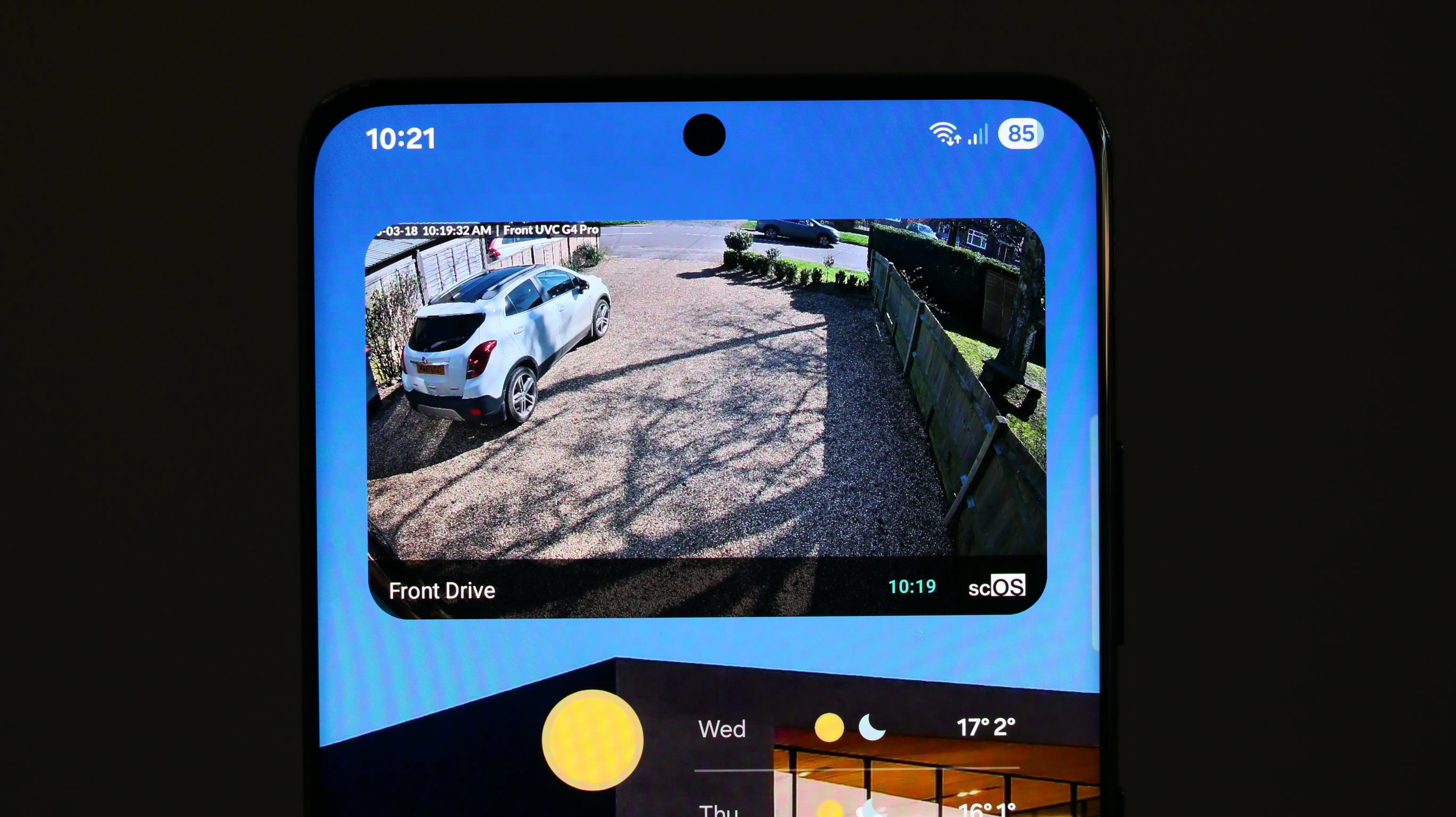 Phone home screen with scOS widget showing live Front Drive camera feed